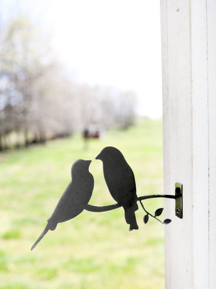 Metal love birds garden statue displayed outdoors among plants