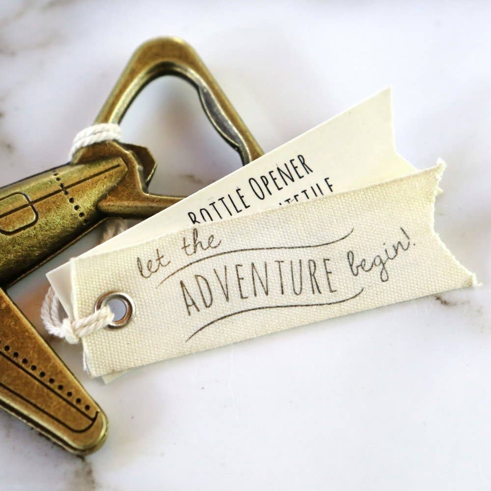Metal bottle opener with a decorative tag on a marble surface