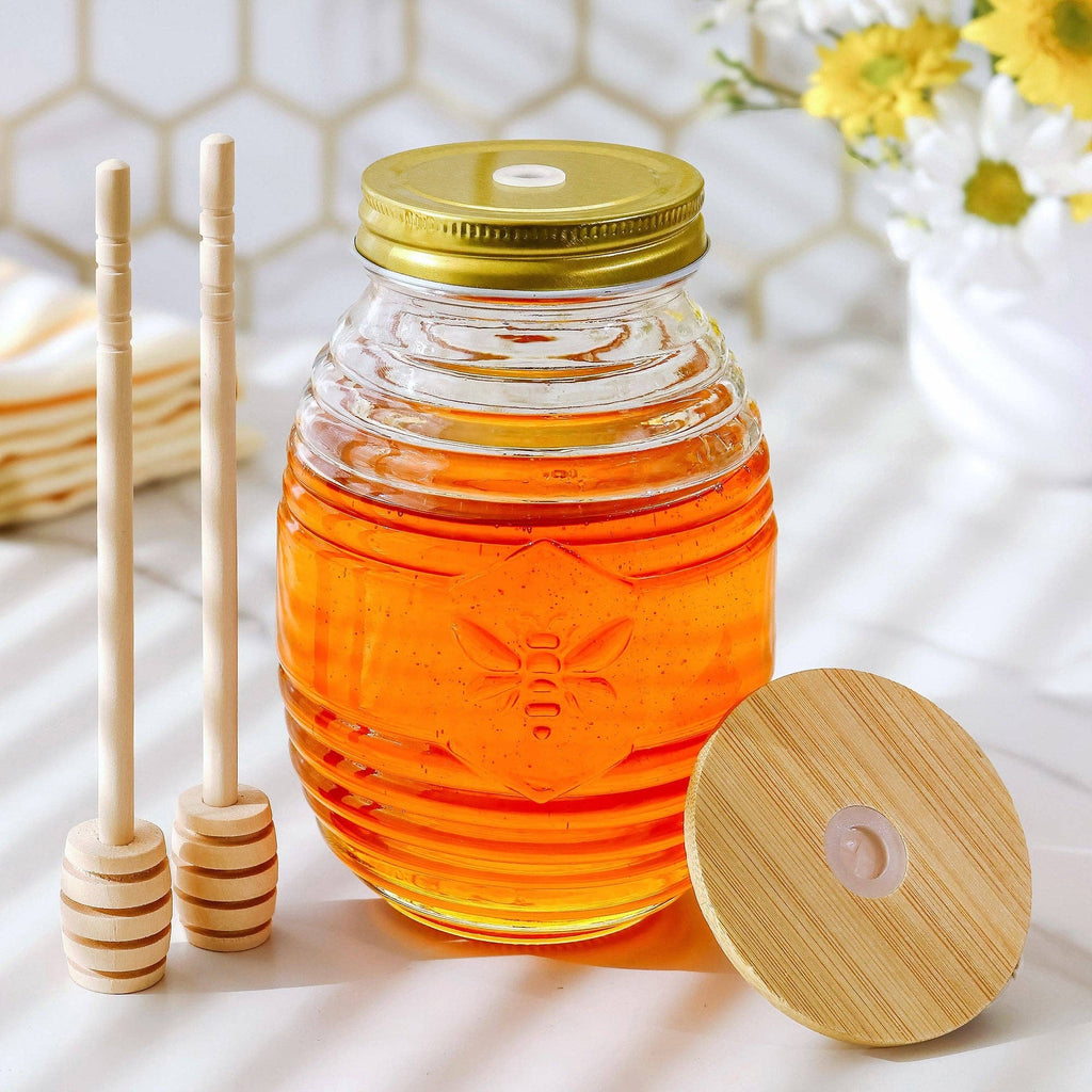 Glass jar of honey with a wooden lid and honey sticks on a light background