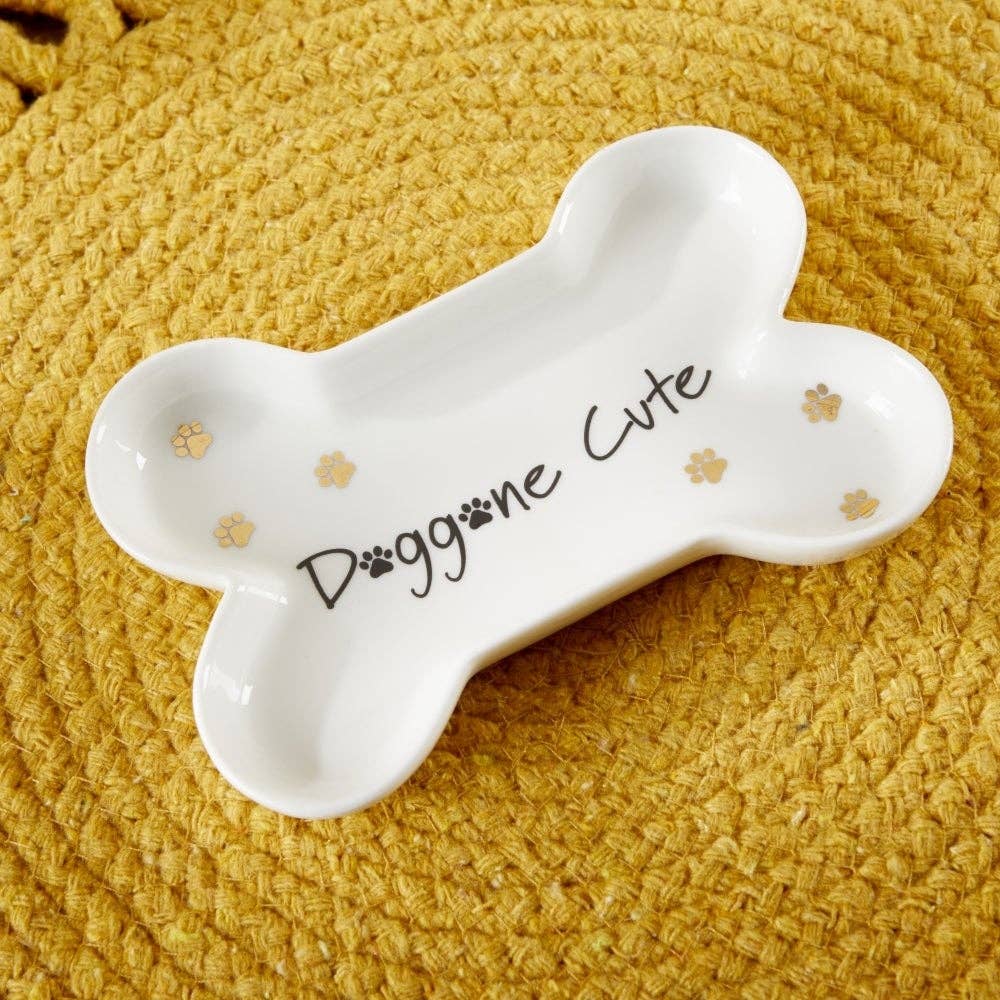 White bone-shaped dish with 'Doggone Cute' text on a textured yellow surface