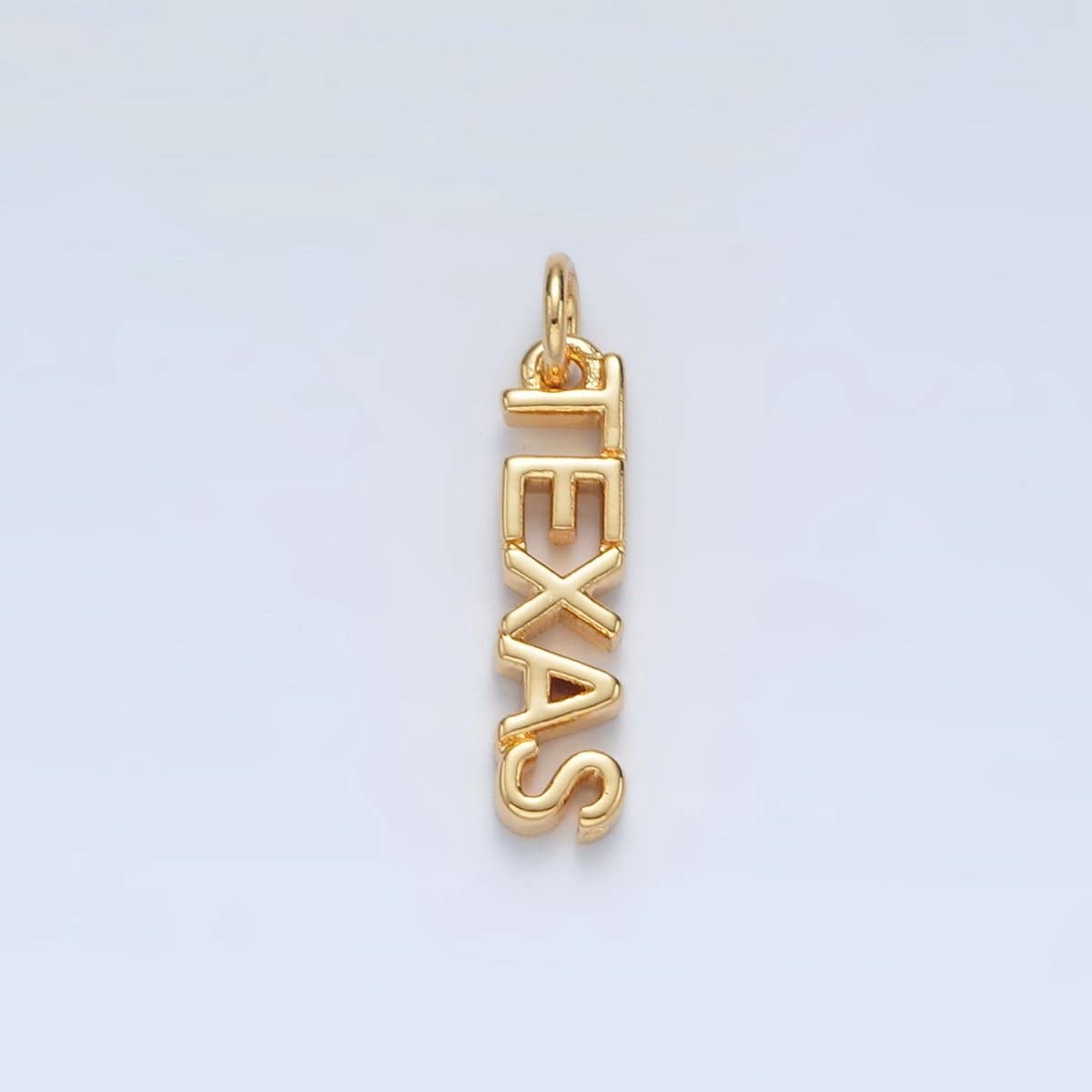 Gold 'TEXAS' pendant on a light gray background