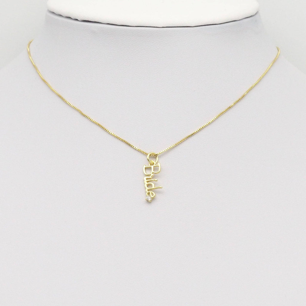 Gold 'Bride' pendant on a gold chain hanging on a mannequin neck