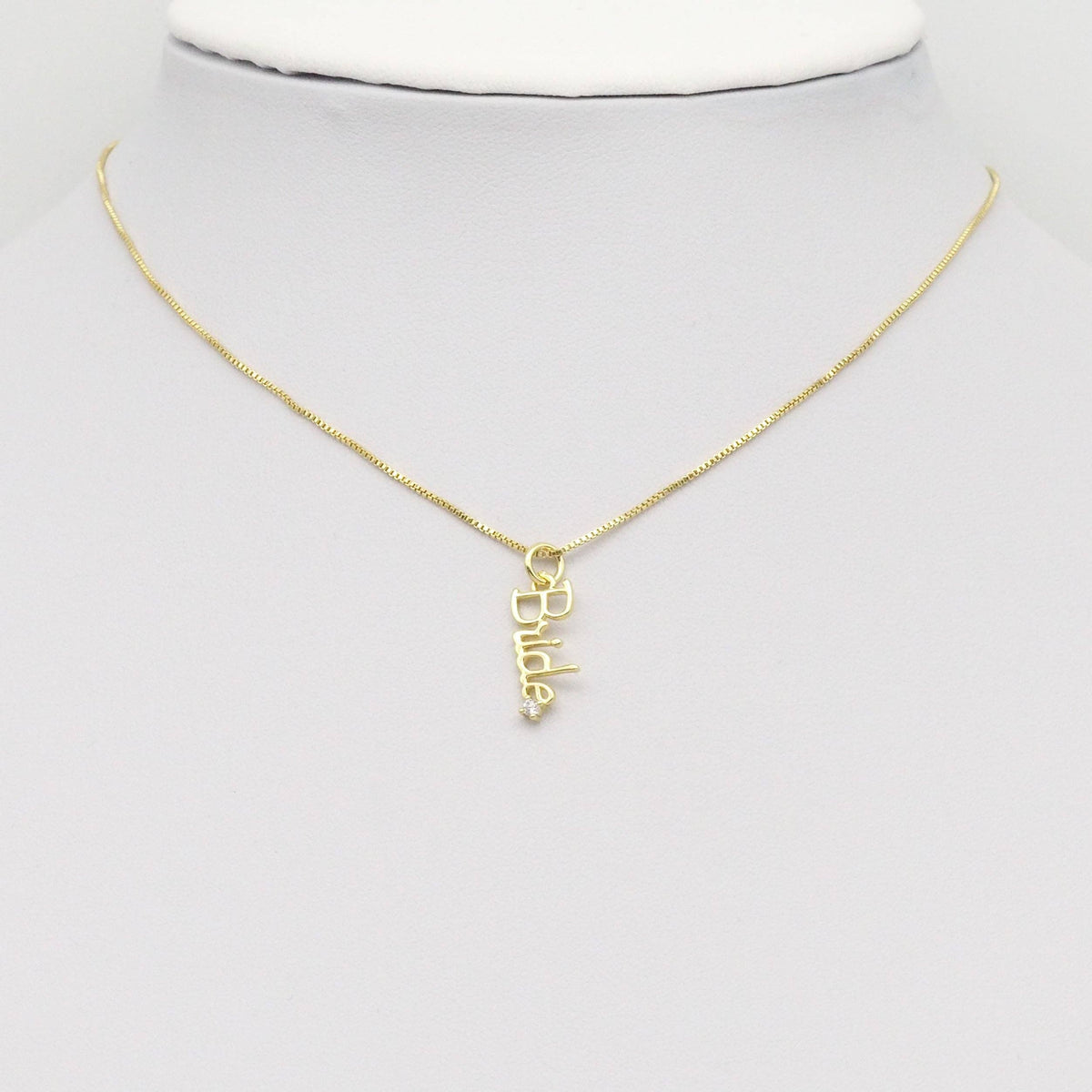 Gold 'Bride' pendant on a gold chain hanging on a mannequin neck
