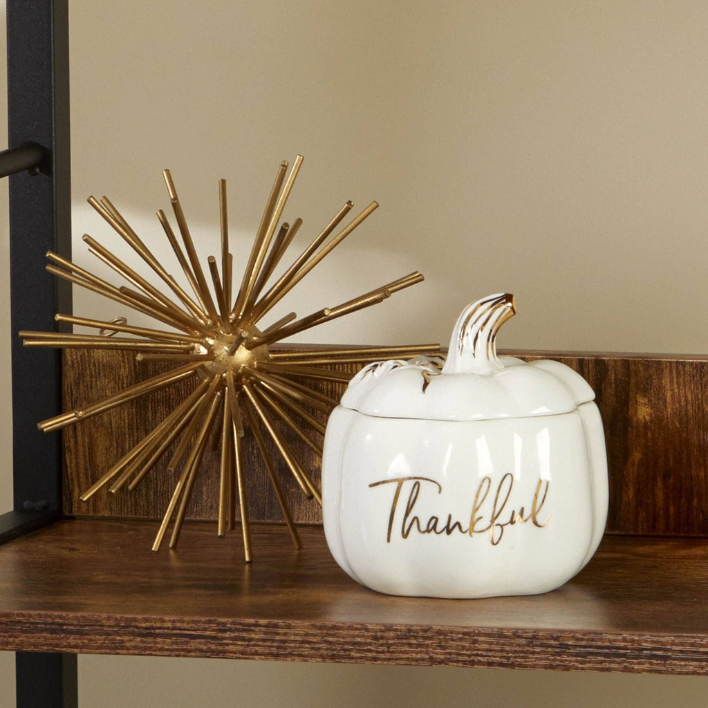 White ceramic pumpkin with 'Thankful' text and gold accents on a wooden surface.