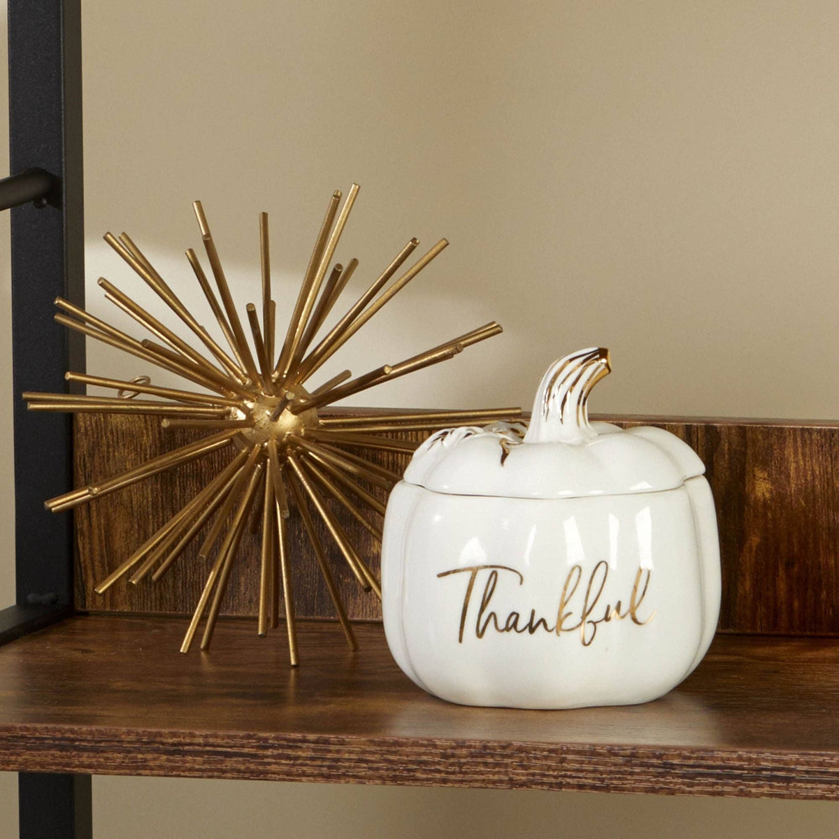 White ceramic pumpkin with 'Thankful' text and gold accents on a wooden surface.