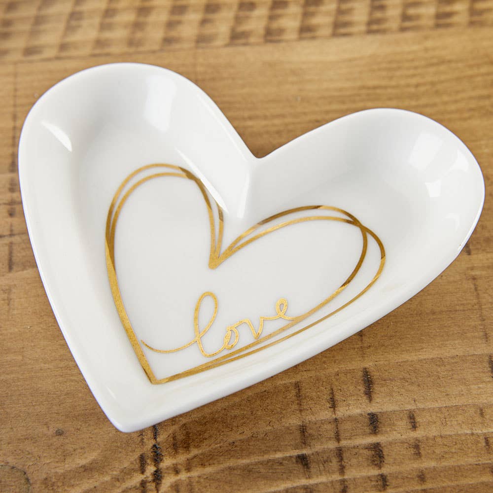 Heart-shaped white dish with gold 'love' engraving on a wooden surface