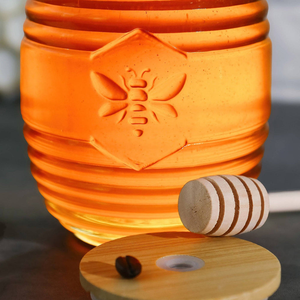Honey jar with a wooden dipper and honeycomb on a reflective surface